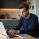 Jeune homme concentré sur son ordinateur dans une cuisine moderne
